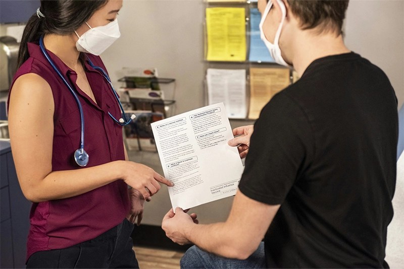A medical staffer wearing a mask assists a patient