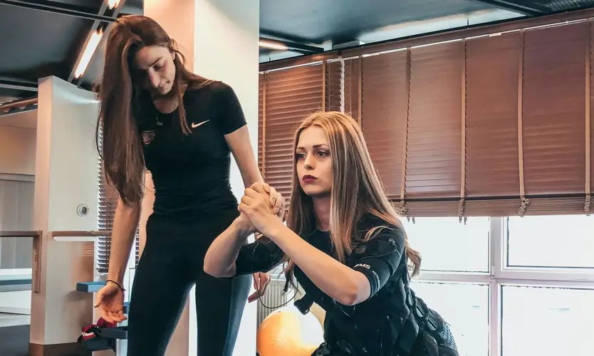 A sports performance coach works with a client in a gym setting