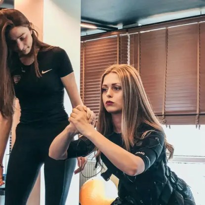 A sports performance coach works with a client in a gym setting