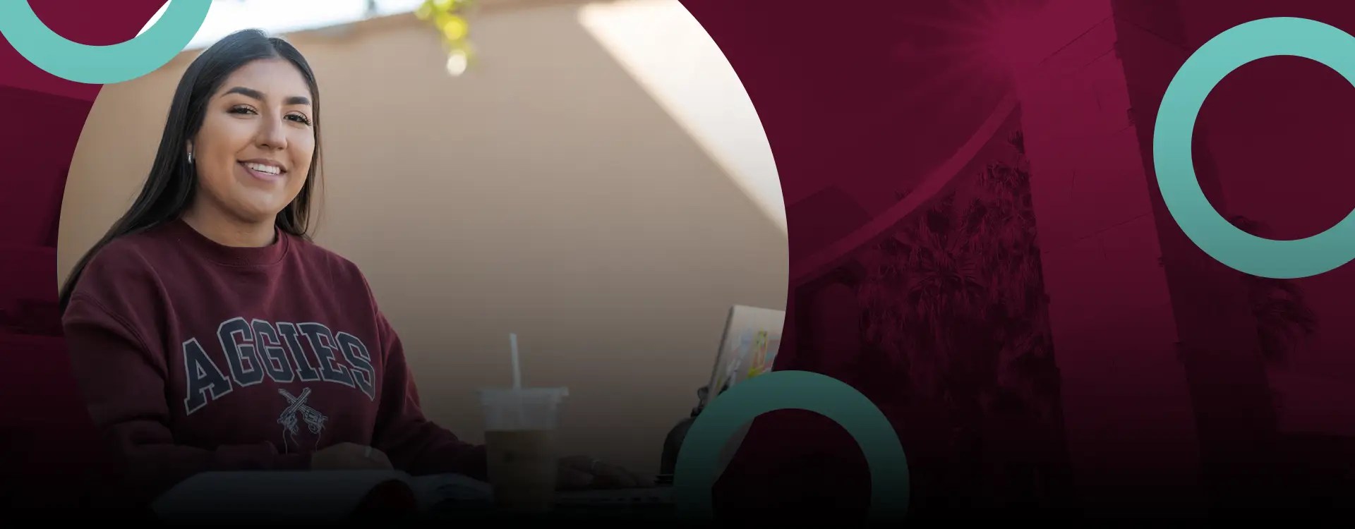 A college student in an NMSU sweatshirt holds her laptop at New Mexico State University Global Campus