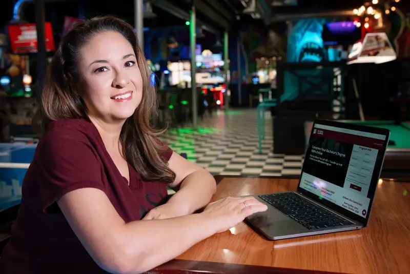 A woman posing next to a laptop computer
