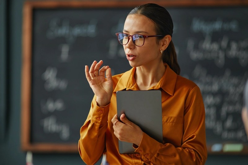 A bilingual Spanish-speaking professional stands in front of a classroom representing online degrees at NMSU Global Campus
